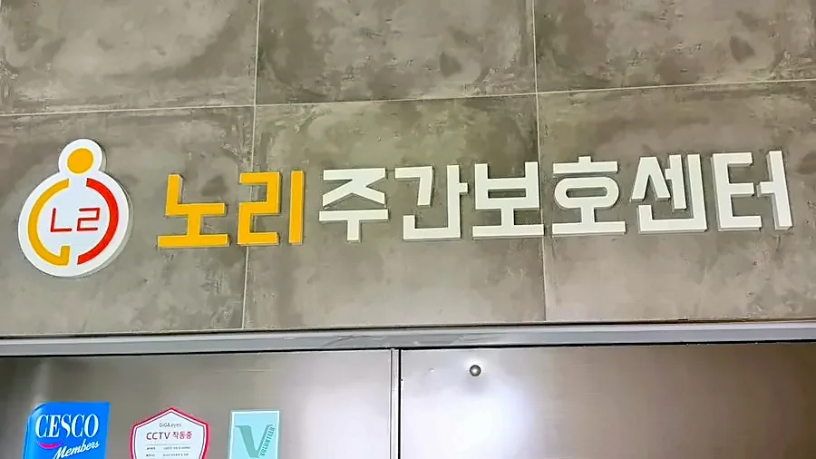 회색 벽에 붙은 노리주간보호센터 로고 간판